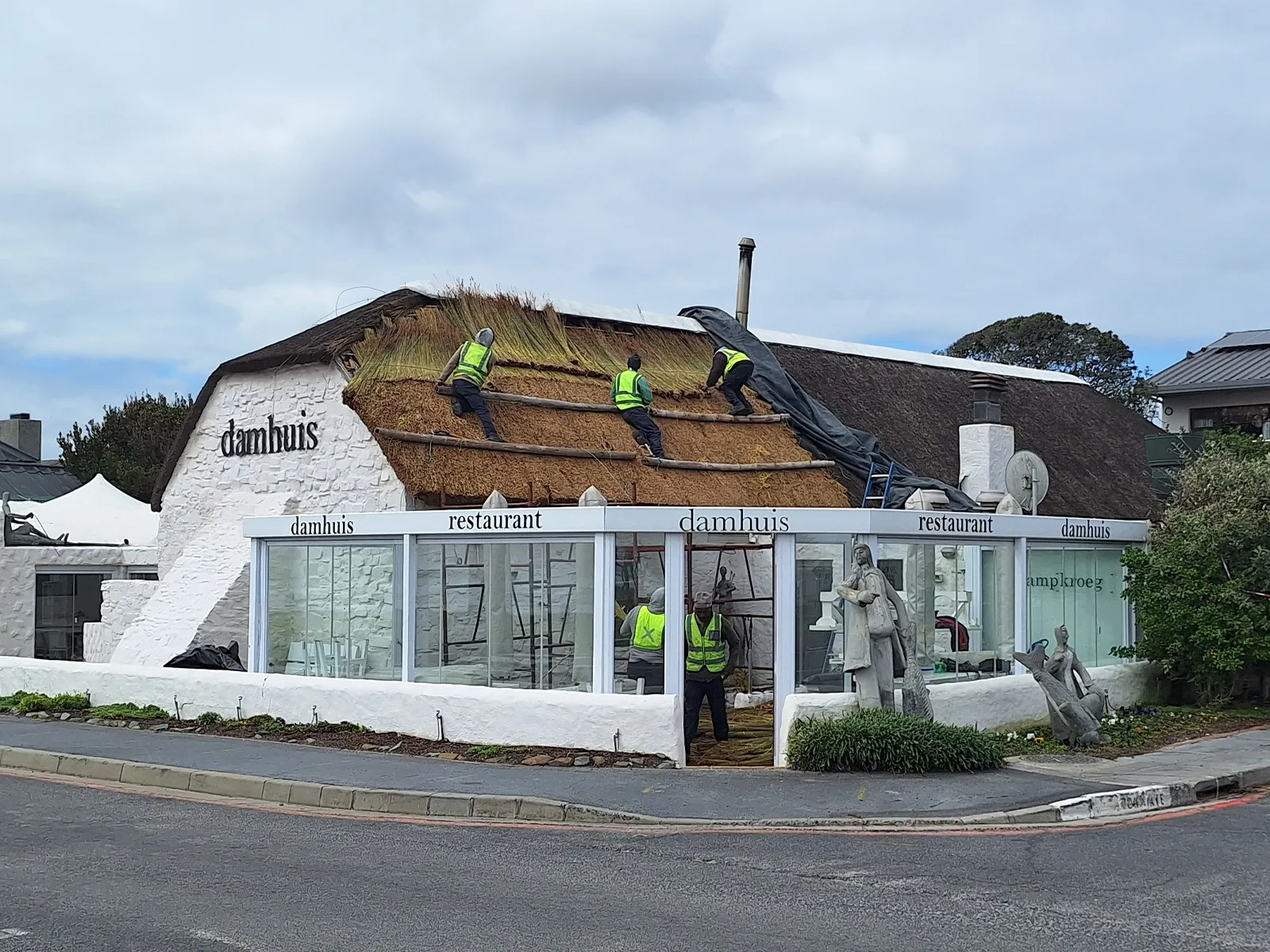 Experienced roofing contractors repairing and re-thatching the roof of a commercial restaurant, demonstrating skilled craftsmanship