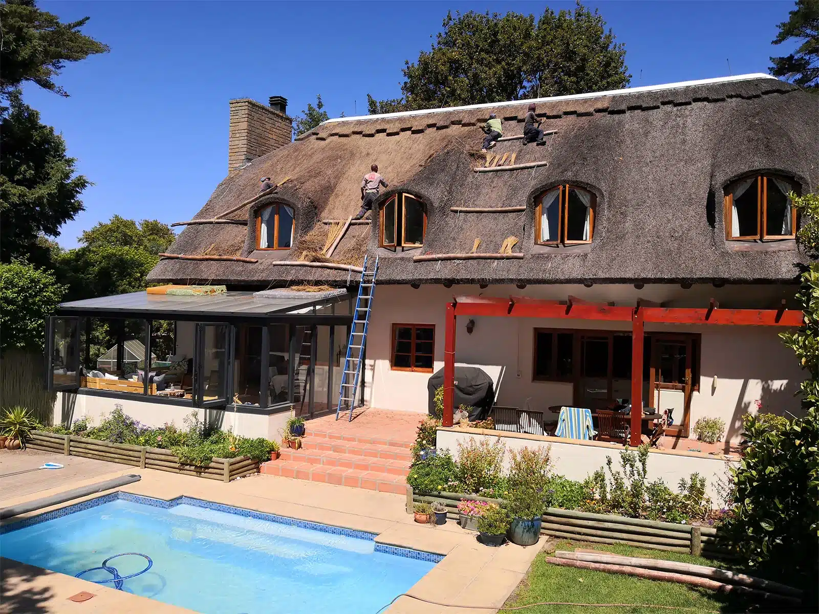 Experienced team providing expert thatch roof overhaul and maintenance services for a suburban home.